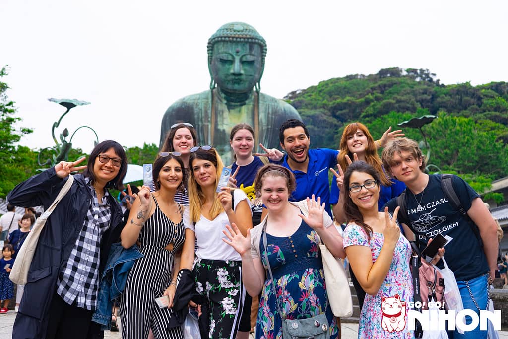 Eine Gruppe von Schülern steht während einer Sprachreise in Japan vor der riesigen Buddha-Statue in Kamakura.