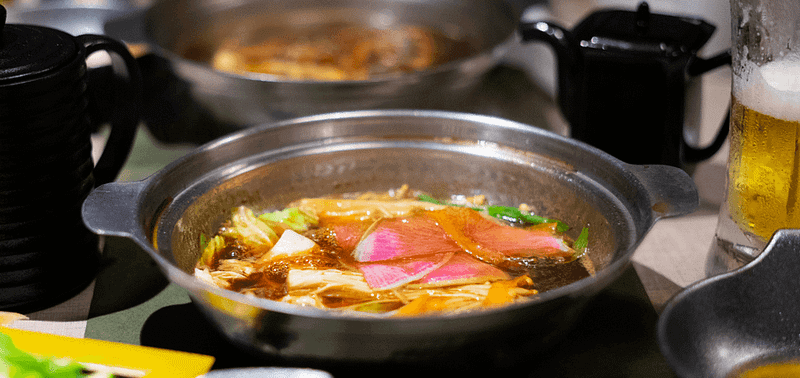 Japanese hot pot shabu shabu boiling in a pot on a table.