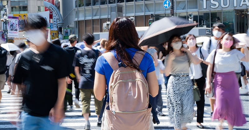 Person wearing a backpack and walking in Shibuya Crossing.