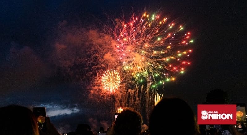 Des gens admirant des feux d'artifice la nuit au Japon en juillet