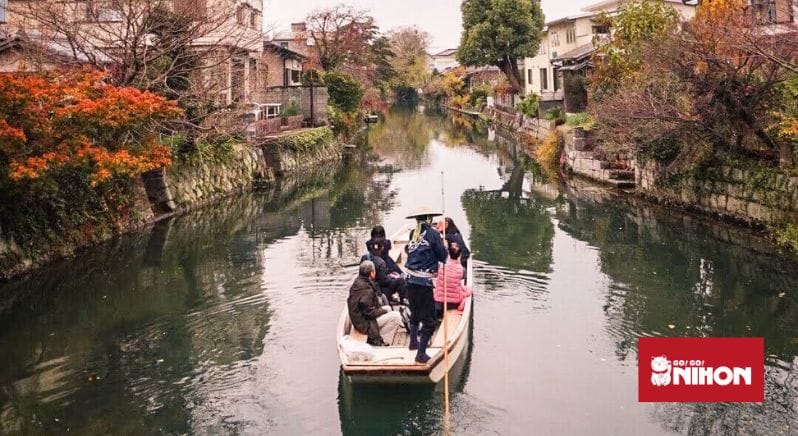 Image of people in a traditional boat going up a river in Yanagawa, Japan
