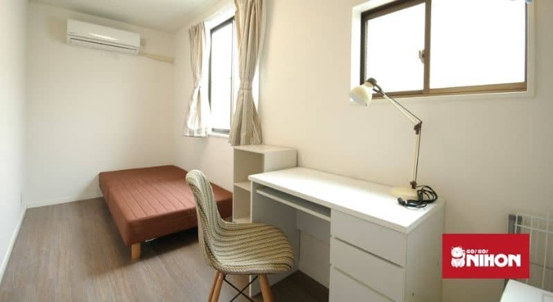 room in a share house with bed, desk, chair and lamp
