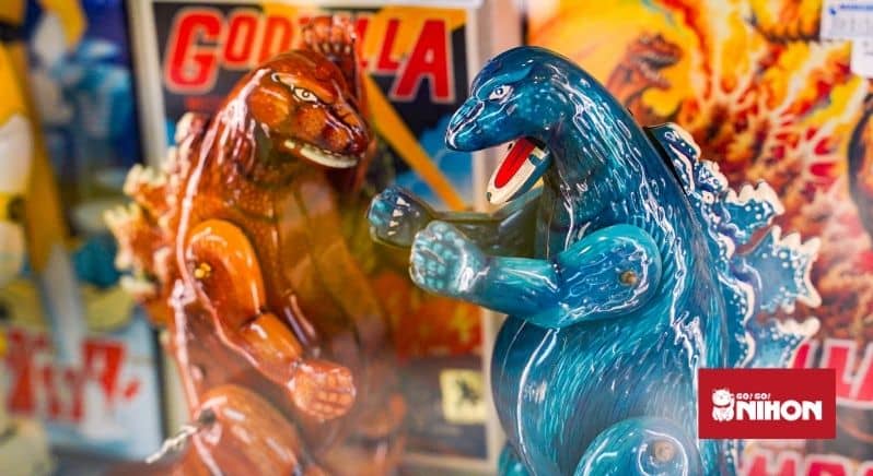 A brown Godzilla figurine next to a blue Godzilla figurine