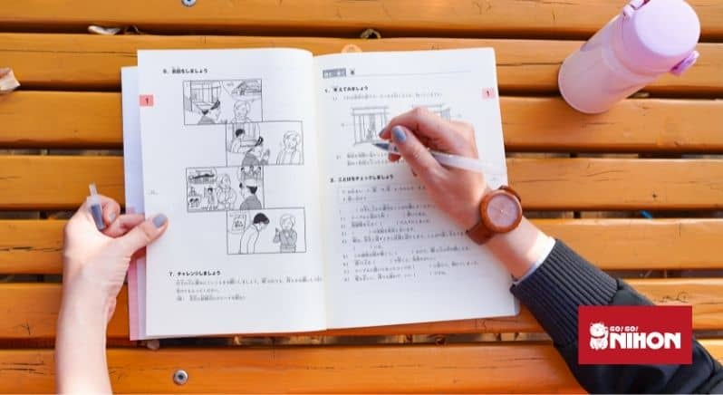 person's hand writing in Japanese textbook