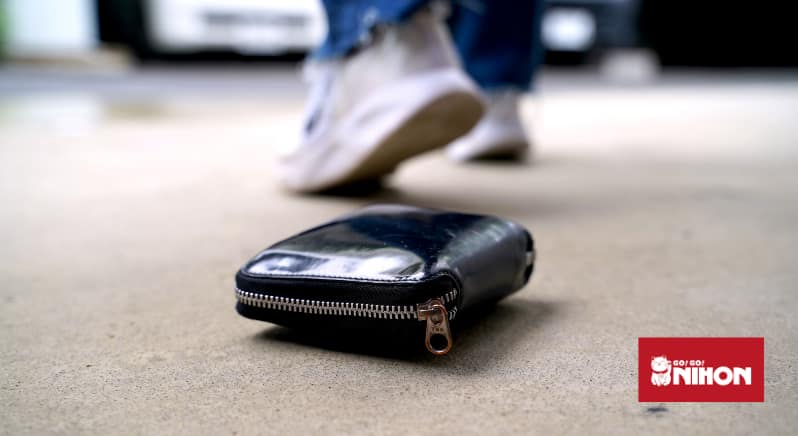 Schwarze Brieftasche auf den Boden gefallen mit einer Person, die im Hintergrund weggeht