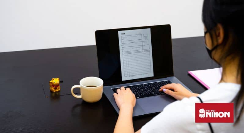 Am Schreibtisch sitzende Person mit geöffnetem Laptop und einem Formular auf dem Bildschirm