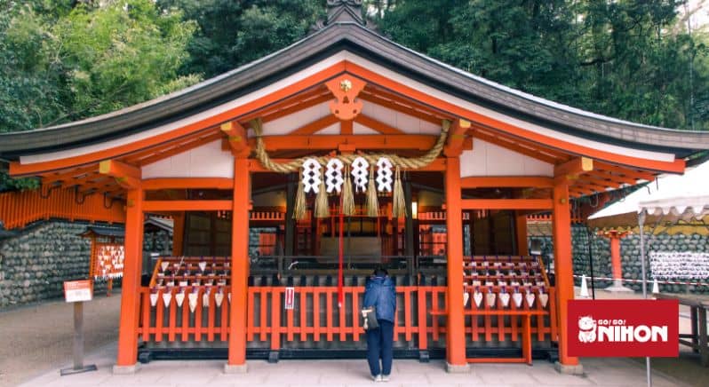 Person praying at a shrine building at Fushimi Inari Taisha in Kyoto