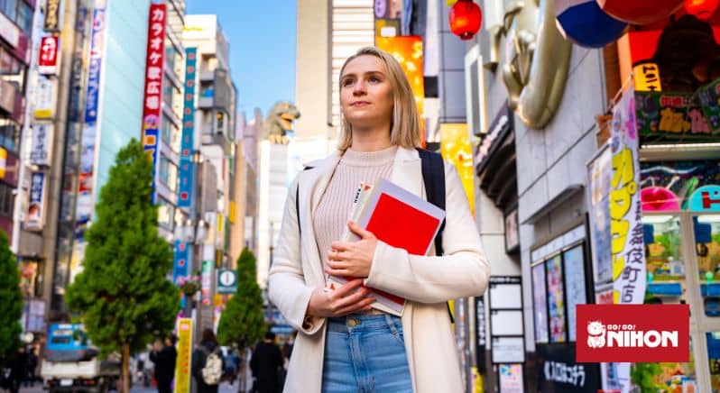Schülerin mit Lehrbüchern, die zum Leben und Lernen in Japan ist, auf der Straße in Shinjuku