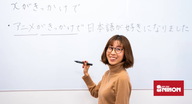Image of Go! Go! Nihon Japanese teacher Yoko Hori standing in front of whiteboard with Japanese characters written on it