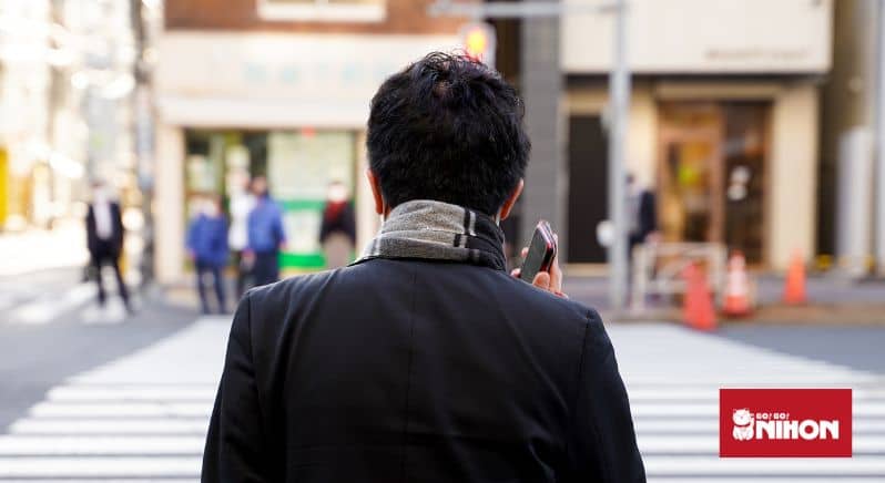 Uma pessoa vista de costas começando a fazer um agendamento em japonês por telefone.