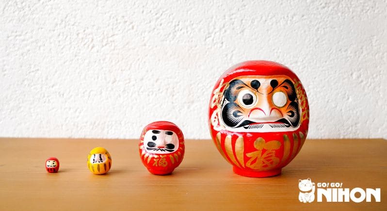 Vier japanische Daruma-Puppen stehen in einer Reihe auf einem Tisch.