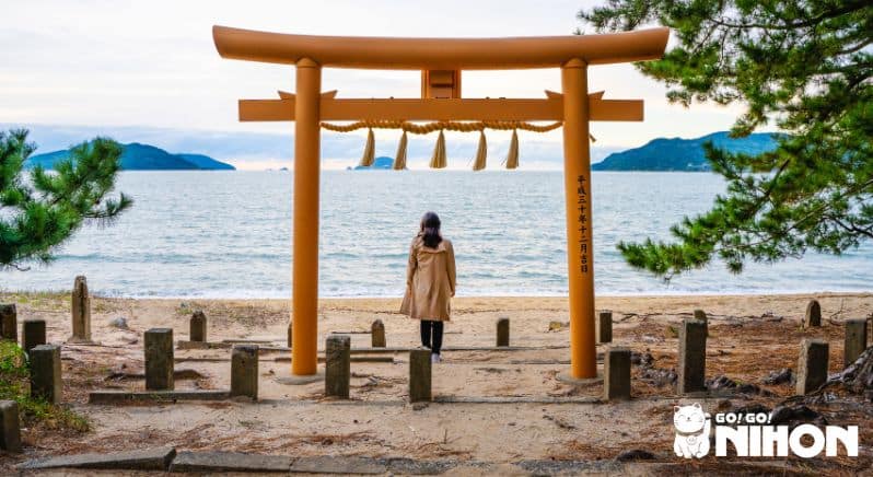 Person in Fukuoka, die vor einem torii-Tor steht.