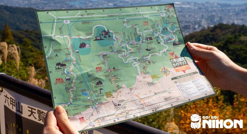 Persona che tiene in mano una mappa di sentieri di montagna in Giappone