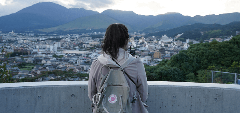 person med ryggsäck tittar från avstånd på en japansk stad