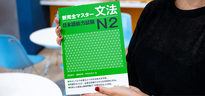 Person in a black shirt holding a JLPT N2